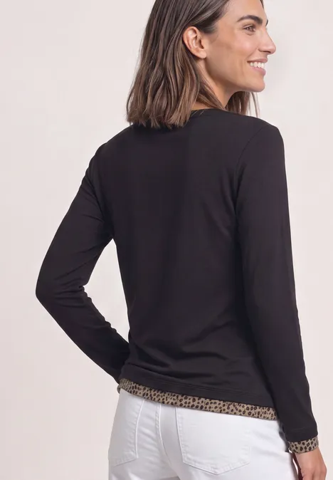 Langarm Shirt mit Colorblock und Printdetail Black Eine Frau von hinten in schwarzem Langarmshirt mit Leo-Besatz und weißer Hose.
