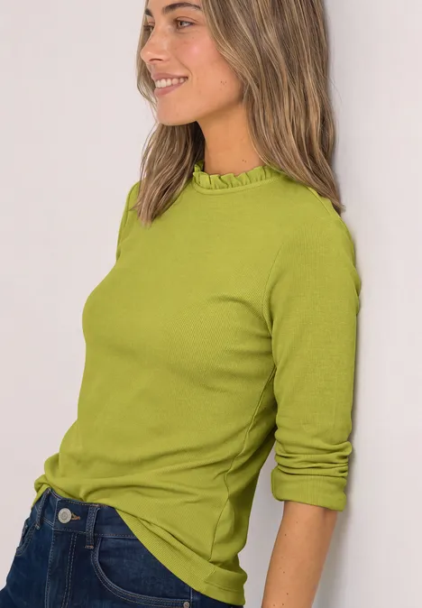 Langarm Shirt mit Rundhals und Rüschen apple lime Frau mit grünem Langarmshirt und Jeans, verschmitzt lächelnd, seitlich stehend.