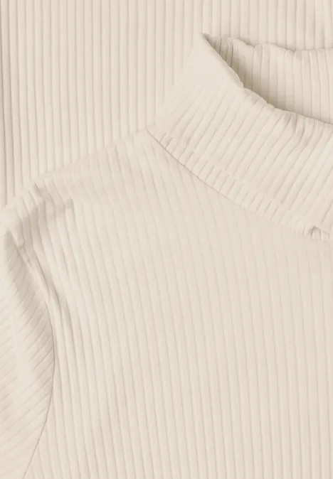 T-shirt basique uni à col roulé pure beige Beiger, fein gerippter Rollkragenpullover vor hellem Hintergrund.