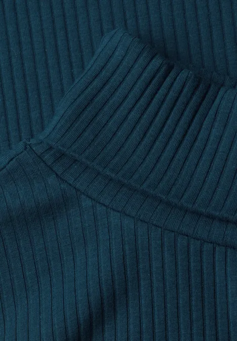 Nahaufnahme eines dunkelgrünen, gerippten Strickrollkragens.