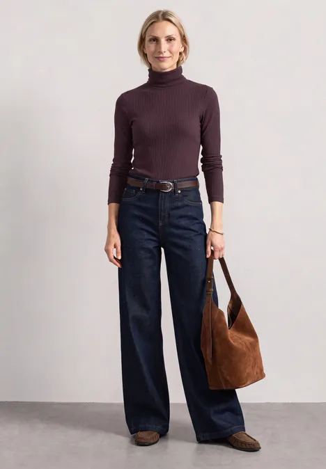 T-shirt basique uni à col roulé berry plum Frau im lila Rollkragenpullover mit weiten Jeans, braunem Gürtel, Tasche und Loafers.
