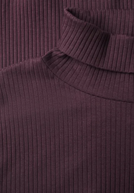 T-shirt basique uni à col roulé berry plum Nahaufnahme eines lila, gerippten Rollkragenpullovers aus weichem Stoff.
