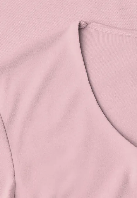 Close-up van een roze bovenstuk met ronde hals en schoudernaad
