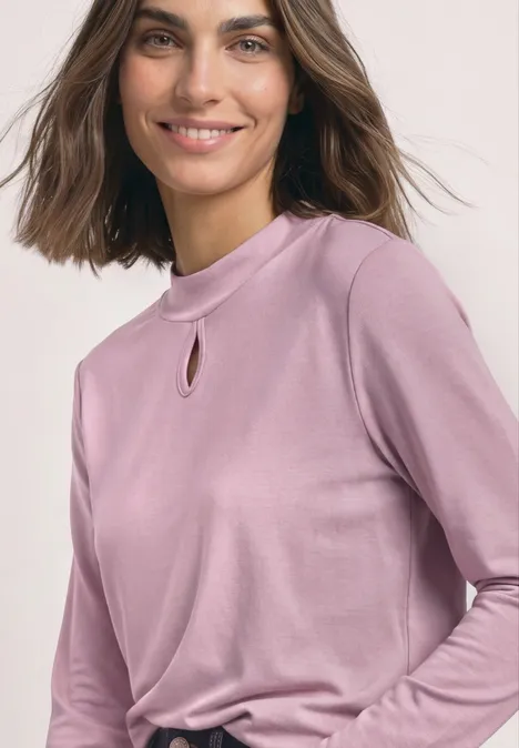 Eine lächelnde Frau in einem hellvioletten Langarmshirt mit kleinem Schlitz am Ausschnitt.