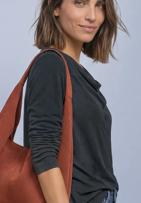 Frau in dunkelgrauem Langarmshirt trägt eine braune Schultertasche.