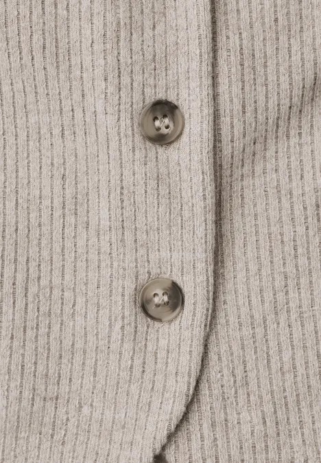 Close-up van beige geribbelde stof met twee bruine knopen.