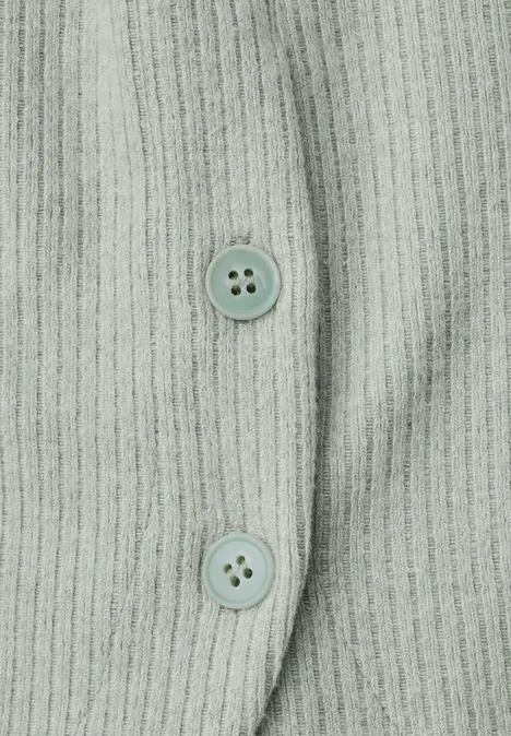 Detail van een lichtgroen geribd gebreid topje met twee bijpassende knopen
