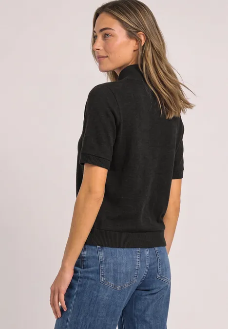 Kurzarm Jacke mit Schalkragen black coffee mel. Frau in schwarzem Kurzarm-Top und blauen Jeans steht seitlich, Blick über die Schulter.