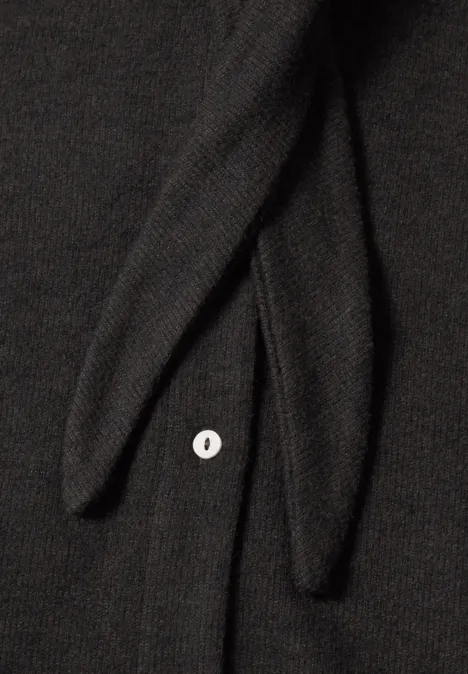 Kurzarm Jacke mit Schalkragen black coffee mel. Nahaufnahme eines schwarzen Strickstücks mit zwei Bändern und einem weißen Knopf.
