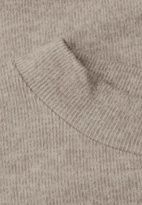 Close-up van een beige gebreide trui met ronde hals.