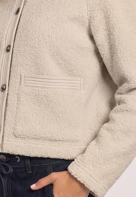 Teddyjasje met structuurdetails clay sand Kort ecru-gekleurde teddy-fleece jack, met knopen en steekzakken, gecombineerd met een donkere broek.