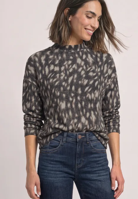 Donkergrijze coltrui met abstracte print, gecombineerd met een high-waist donkere spijkerbroek.