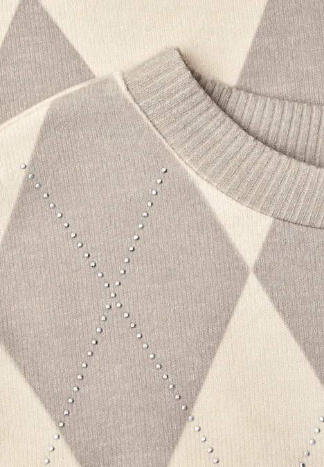 Close-up van een grijs-beige argyle trui met geribde hals en fonkelende studs in X-vorm.
