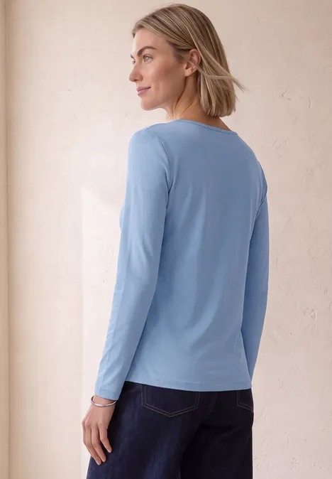 Basic Shirt mit U-Boot-Ausschnitt northern blue Frau mit schulterlangem blonden Haar trägt ein hellblaues Langarmshirt und blickt seitlich über die Schulter.