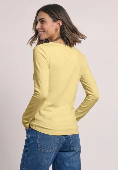 Basic Shirt mit U-Boot-Ausschnitt sunbeam yellow Frau von hinten in gelbem Langarmshirt und blauen Jeans, mittellange braune Haare, dezent lächelnd.