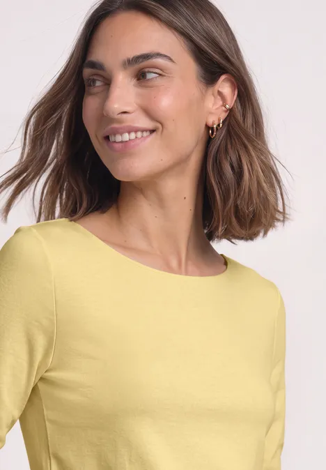 Basic Shirt mit U-Boot-Ausschnitt sunbeam yellow Eine lächelnde Frau mit schulterlangen braunen Haaren in einem gelben Oberteil.