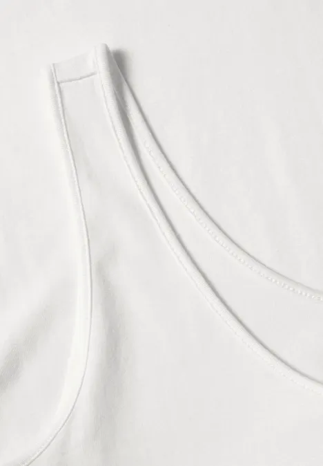 Nahaufnahme eines weißen Tanktops mit Rundhalsausschnitt auf hellem Untergrund.