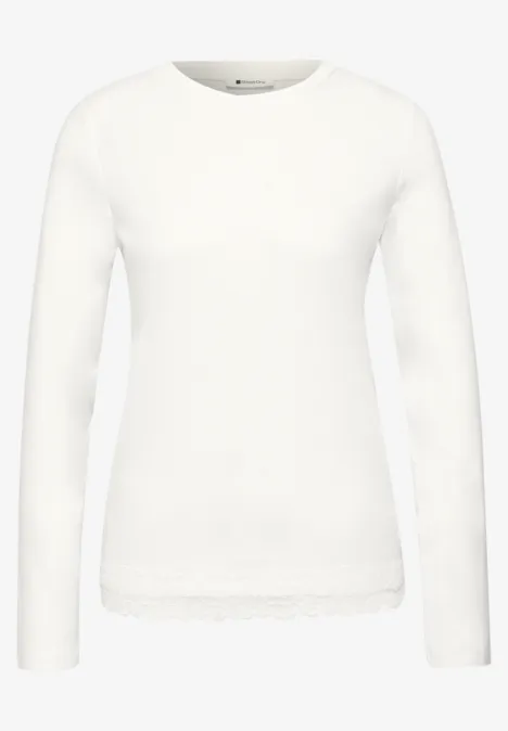 Weißes Langarmshirt mit Rundhalsausschnitt und Spitzenbesatz am Saum.
