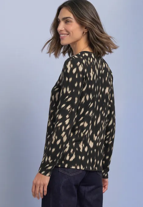 Langarm Shirt mit Rundhals und Rehmuster Black Frau in schwarzer Bluse mit beigen Flecken und dunkler Hose lächelt seitlich.