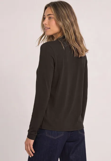 Langarm Shirt im Blusen-Look black coffee Frau mit schwarzem Langarmshirt und blauer Jeans, seitlich blickend vor hellem Hintergrund.