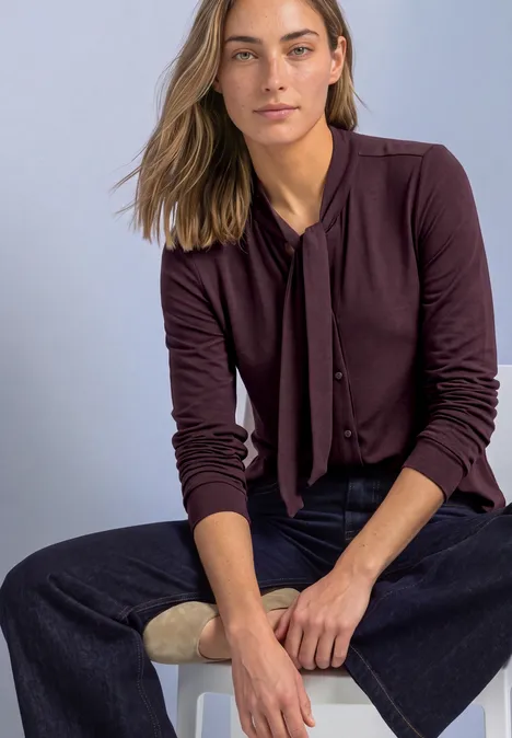 Langarm Shirt im Blusen-Look berry plum Frau in weinrotem Cardigan mit Schleife am Kragen und weiten dunklen Jeans sitzt entspannt
