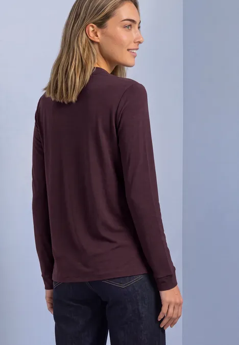 Langarm Shirt im Blusen-Look berry plum Frau von hinten in braunem Langarmshirt und dunkler Jeans vor neutralem Hintergrund.