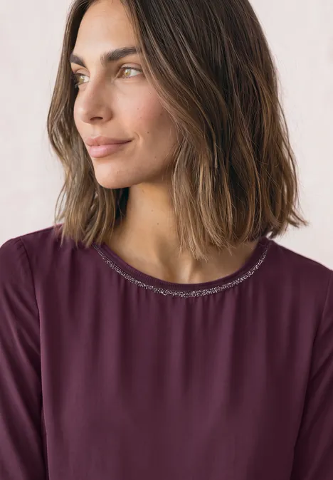 2-in-1 Sirt aus Chiffon mit Boat Neck berry maroon Portrait einer Frau mit schulterlangem braunem Haar und burgunderfarbenem Shirt, seitlich blickend.