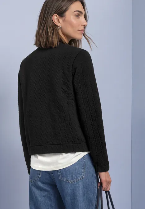 Leichte Sweatjacke mit Struktur und Zipper Black Frau von hinten mit schwarzem Blazer, weißem Shirt, blauen Jeans und Tasche.