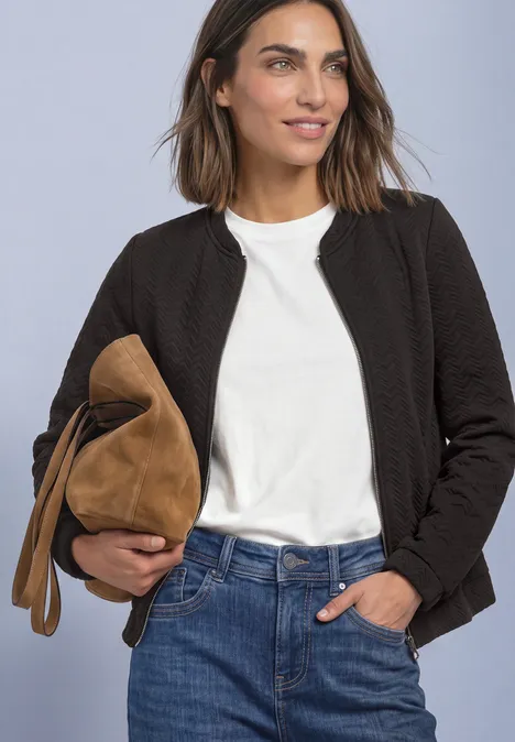 Leichte Sweatjacke mit Struktur und Zipper black coffee Frau in weißem T-Shirt, schwarzer Jacke, blauen Jeans, hält braune Veloursledertasche.