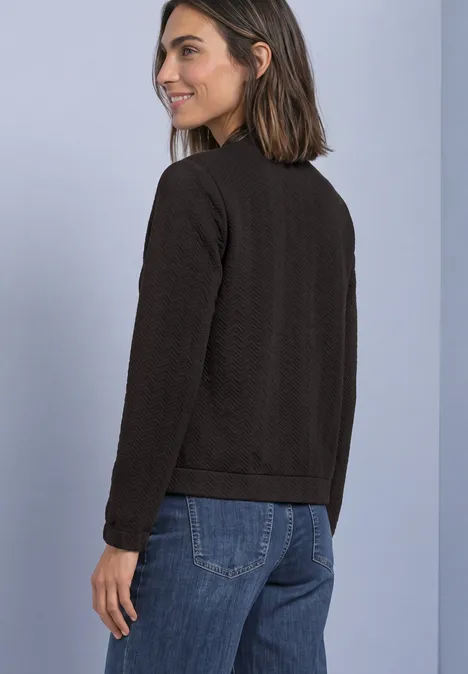 Leichte Sweatjacke mit Struktur und Zipper black coffee Frau trägt schwarzen Pullover und Jeans, seitlich stehend, im Profil lächelnd vor neutralem Hintergrund.
