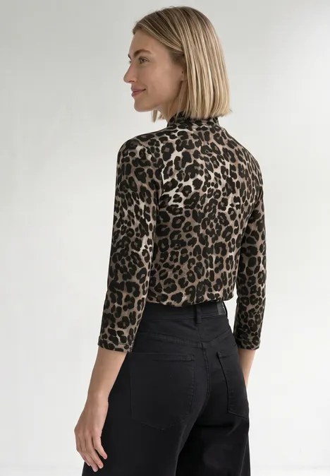 Femme de profil portant un col roulé imprimé léopard et un pantalon noir.