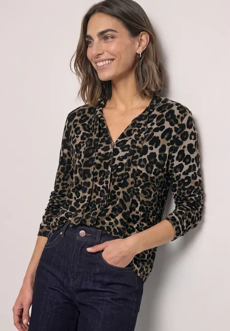 Langarm Shirt im Blusen-Look mit Leo-Muster Black Frau trägt schwarzen Pullover mit Leopardenmuster und Jeans.