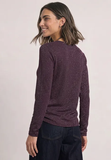 Langarm Shirt mit Boat Neck und Glitzer berry plum Eine Frau in dunkelviolettem Pullover und Jeans, von hinten fotografiert, schaut über die Schulter und lächelt.