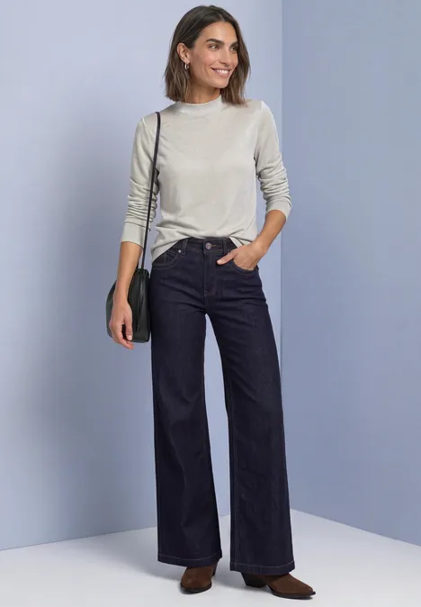 Femme en pull gris clair, jean taille haute et ample, sac bandoulière noir et chaussures marron.