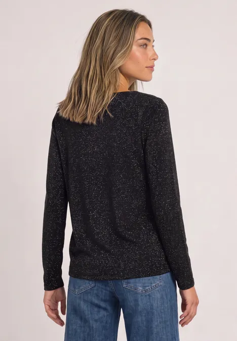 Langarm Shirt mit Wasserfallfront Black Frau steht mit dem Rücken zur Kamera, trägt schwarzen Glitzershirt und blaue Jeans vor hellem Hintergrund.