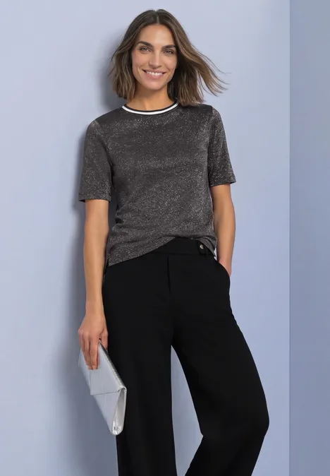 Kurzarm Shirt mit Rundhals und Glitzer black coffee Eine lächelnde Frau vor blaugrauem Hintergrund in silbernem Kurzarmshirt, schwarzen Hosen und grauer Clutch.