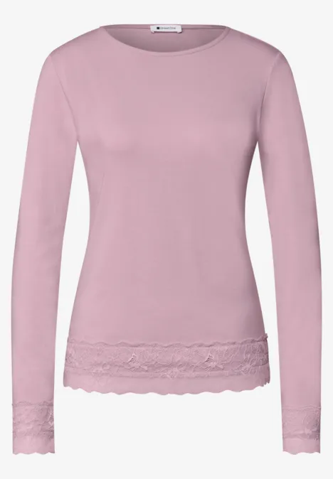 T-shirt à manches longues rose avec bordure en dentelle à la base et aux manches.