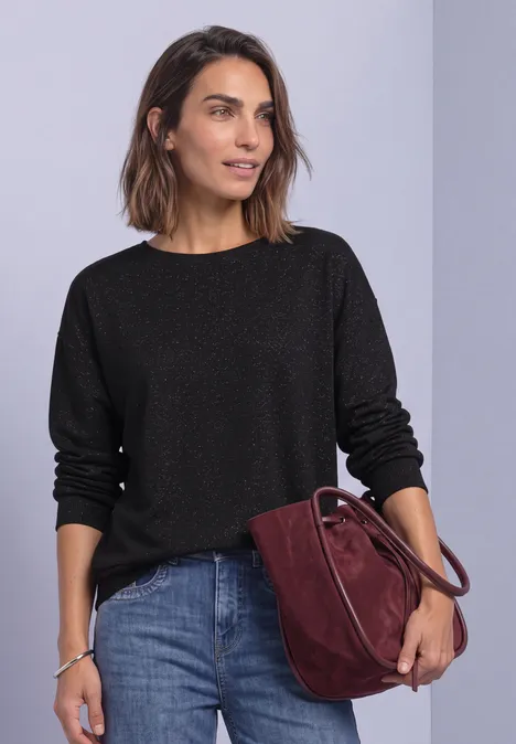 Shirt met gebreide look en vleermuismouwen Black Een vrouw draagt een zwarte trui, spijkerbroek en een donkerrood tasje voor een lichte achtergrond.