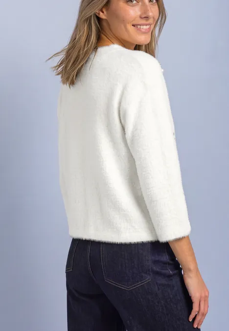 3/4-Arm Shirt mit dekorativen Details off white Eine Frau von hinten in einem weißen Pullover und dunklen Jeans, die über die Schulter lächelt.
