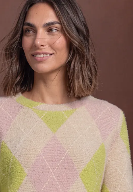 Frau mit braunen Haaren trägt Pullover mit Rautenmuster in Grün und Rosa.