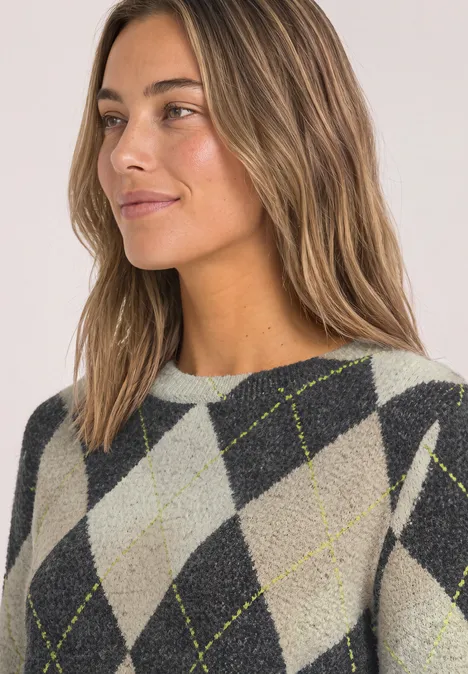Frau mit leicht gewelltem hellbraunem Haar in grauem Argyle-Pullover mit gelben Linien.