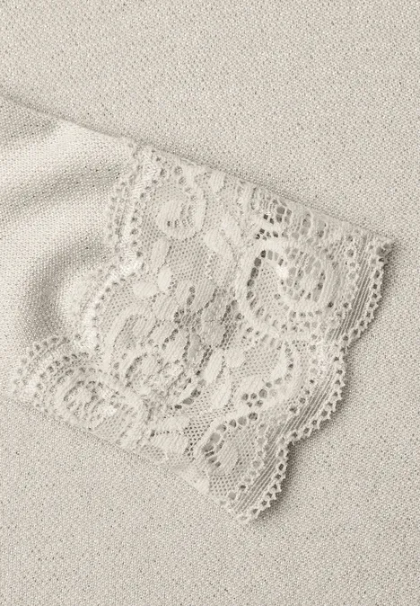 Shirt met glitters en kant pure beige Close-up van een beige kanten stof met een gedetailleerde kanten boord.