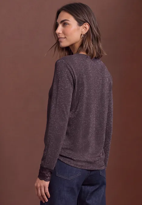 Shirt met glitters en kant berry plum Vrouw in paarse trui met lange mouwen en spijkerbroek, zij-aanzicht tegen bruine achtergrond.