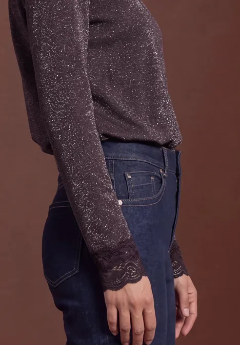 Shirt met glitters en kant berry plum Zijaanzicht van een persoon in glinsterende lange mouw top met kant en blauwe spijkerbroek, bruine achtergrond.