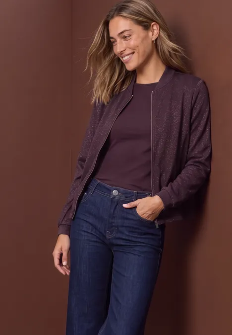 Leichter Blouson mit Glitzerdetails berry plum Frau in lila Bomberjacke und Jeans, vor braunem Hintergrund lächelnd in die Tasche greifend
