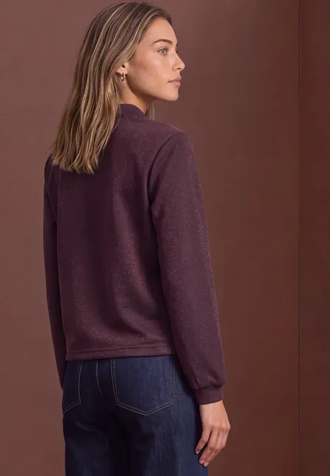 Leichter Blouson mit Glitzerdetails berry plum Seitlich stehende Frau in bordeauxrotem Pullover und Jeans vor braunem Hintergrund.