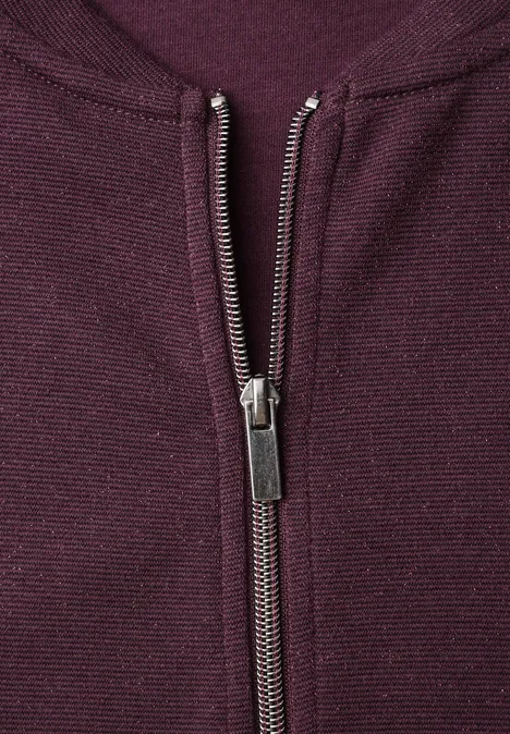 Leichter Blouson mit Glitzerdetails berry plum Nahaufnahme eines lila Textilreißverschlusses an einem Strickstoff.