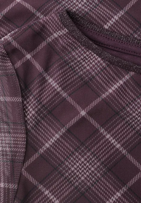 Gros plan sur un tissu à carreaux bordeaux avec une couture apparente