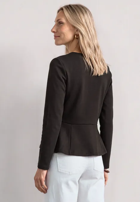 Langarm Shirt mit Volant-Saum black coffee Eine blonde Frau von hinten, trägt schwarzen Blazer und weiße Jeans, steht seitlich und blickt zur Seite.