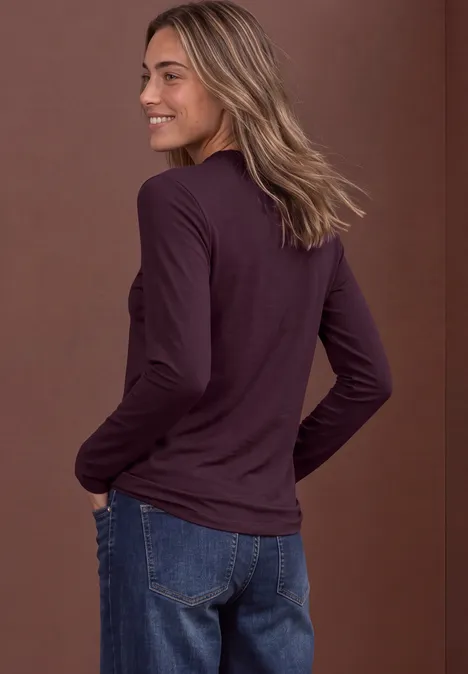 Shirt met lange mouwen, col en mesh-detail berry plum Eine lächelnde Frau im Profil trägt ein langärmeliges, dunkelviolettes Shirt und blaue Jeans.
